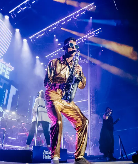 Saxophonist lit by spotlight, playing a smooth solo during SYNTHONY.